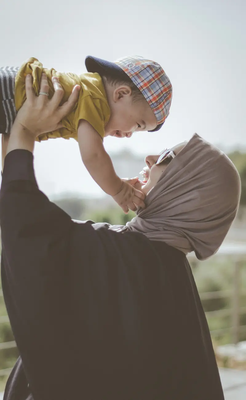 A mother lifting her smiling baby into the air