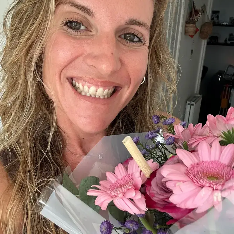 Sylvia smiling, holding a bouquet of pink flowers